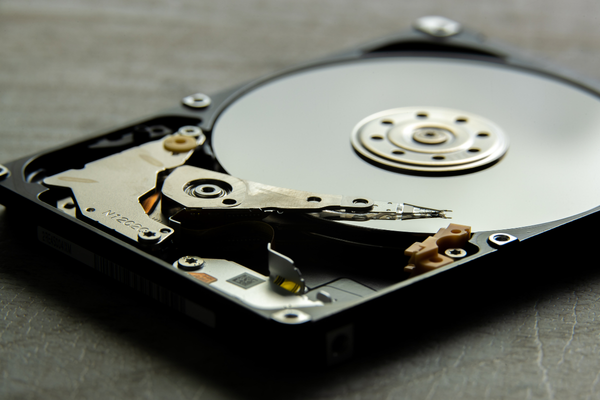 Close-up of an exposed hard drive platter and actuator arm, illustrating the internal structure of magnetic storage media for the article: will a magnet destroy a hard drive.