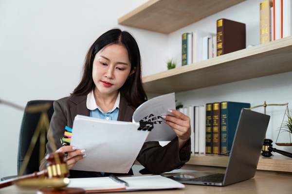 law firm data destruction requirements — law firm staff member reviewing a client file at a desk with paper documents, a laptop, and legal reference books in the background.